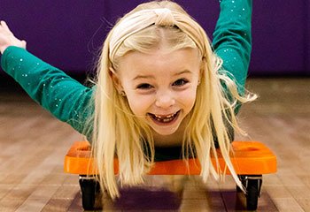 Small girl riding a wheelie cart