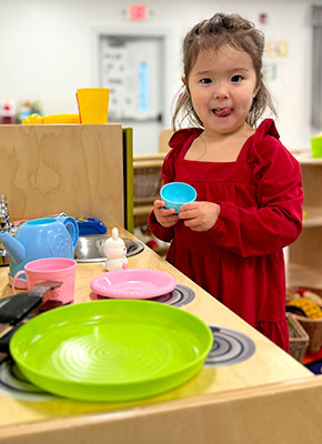 Small girl playing with kitchen set in playroom