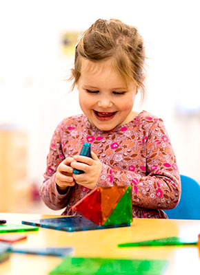 Small girl playing with a puzzle in a classroom