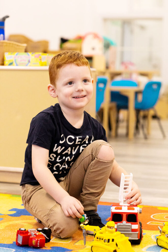 Small boy playing with a fire truck in a classroom