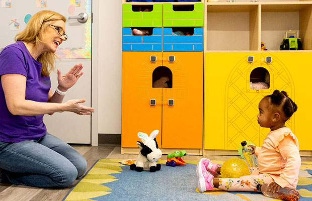 Teacher singing song with toddler in classroom